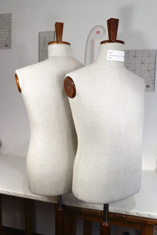 Manekiny krawieckie regulowane w pracowni: z drewnianymi detalami, metalowymi stojakami, etykieta 'Katarzyna Anna', tło z siatką pomiarową